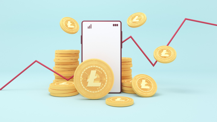 monety symbolizujące kryptowalutę Litecoin, telefon komórkowy i rosnący wykres