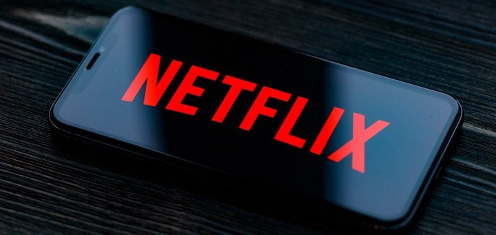 Cellulare nero con sfondo del logo in rosso Netflix, che potrebbe indicare comprare azioni Netflix.