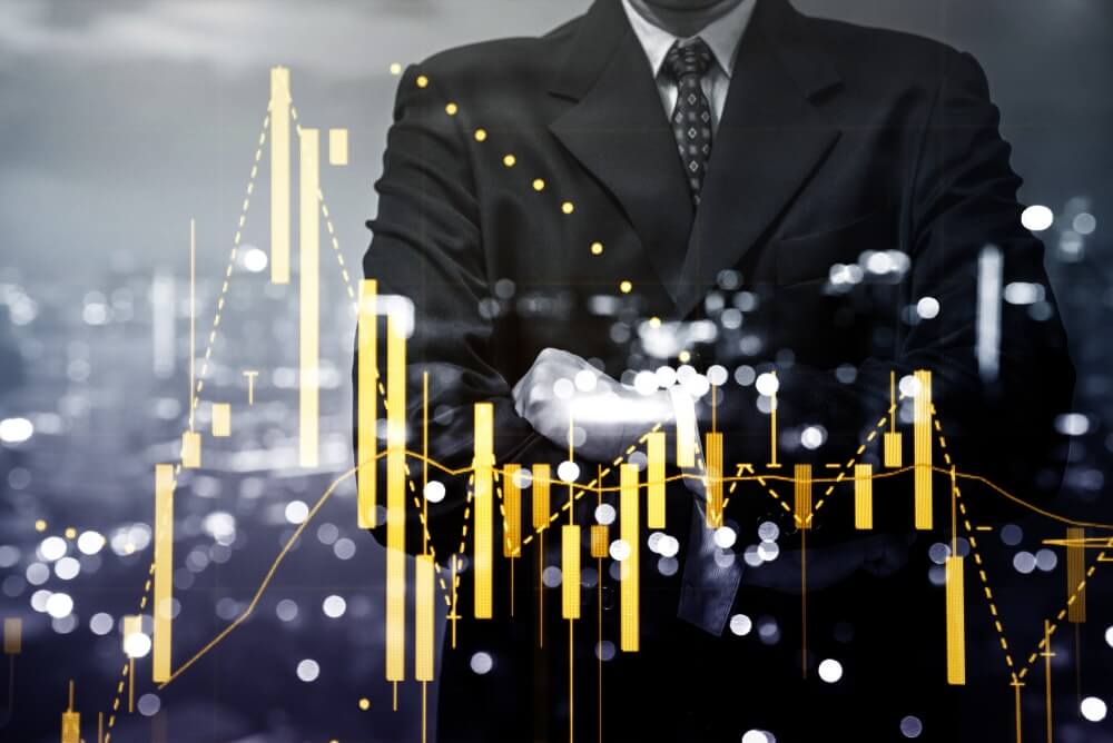 Voorgrond een grafiek met gele candlesticks en trendlijnen, op de achtergrond een man in pak en das, verwijzend naar het beleggen in Duitse staatsobligaties of Duitse Bund CFD's.