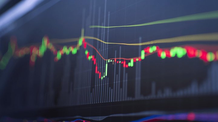 Sfondo di uno schermo con un grafico candlestick e altri grafici trading che indicano il Martingala Trading.